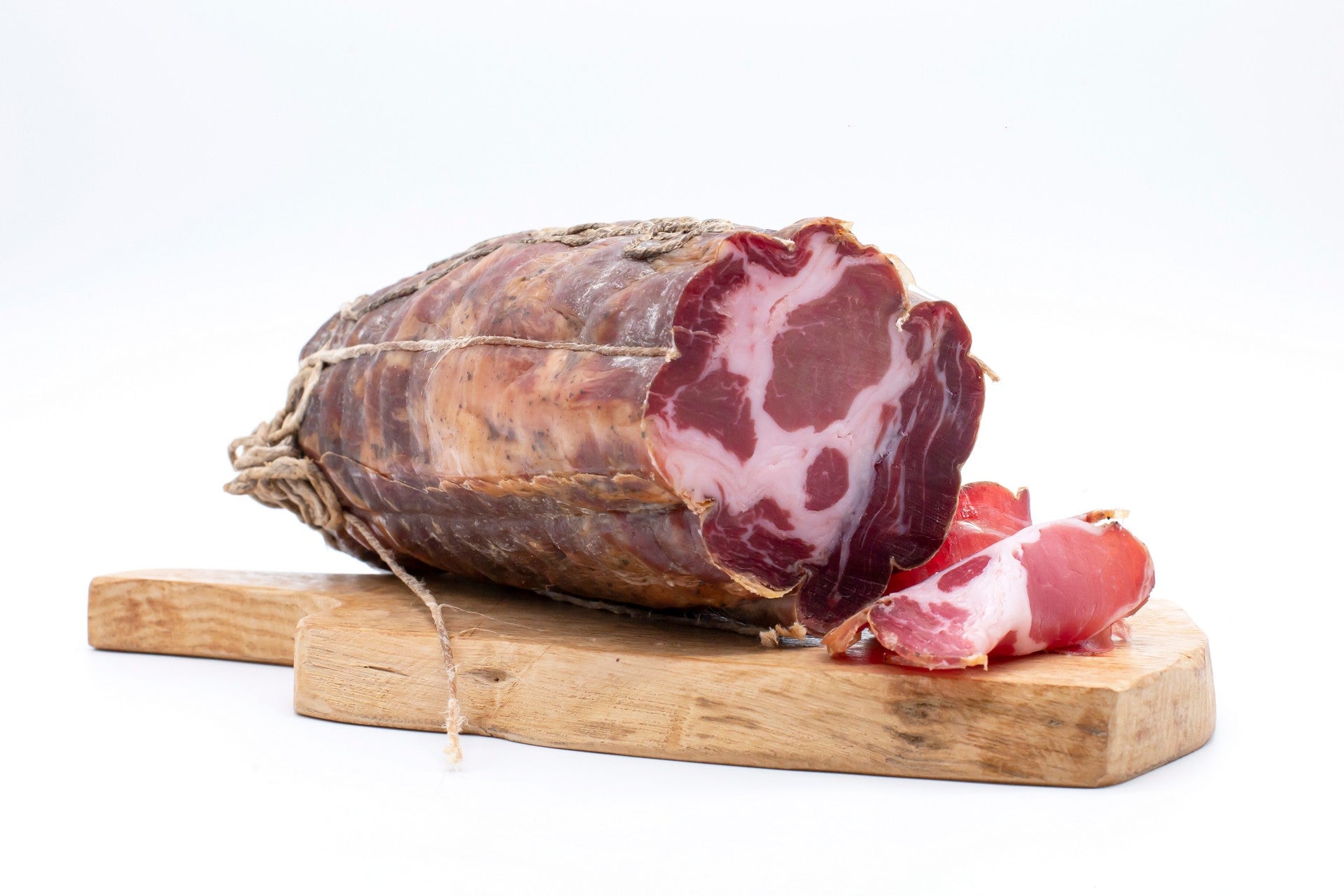 Capocollo intero di Cirigliano da 500 grammi su un tagliere in legno, pronto per il taglio a coltello.