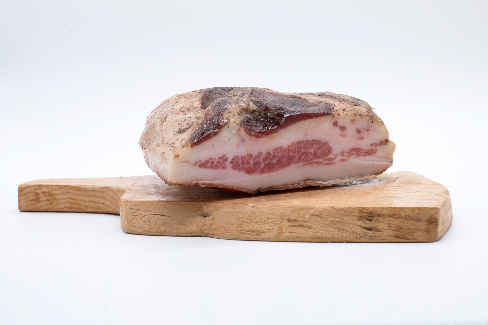 Trancio di guanciale artigianale di Cirigliano da 500g di Sapori Mediterranei su tagliere, con strati di grasso bianco e magro rosa. Selezionato da Borgo Calvera.